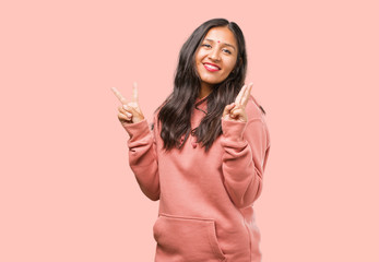 Portrait of fitness young indian woman fun and happy, positive and natural, doing a gesture of victory, peace concept