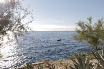 Boat, motorboat on the Adriatic Sea. Beautiful weather. Sunny, hot, summer day on the Croatian coast. Primosten, Croatia. Rocky shore, mediterranean vegetation, riviera, seashore.