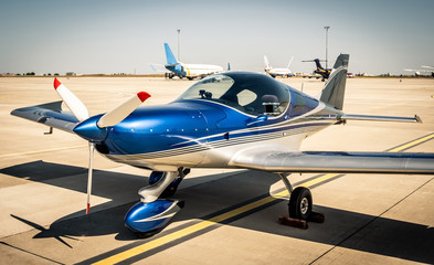 Fototapeta na wymiar Shiny blue sport plane at the airport sunshine runway
