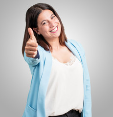 Middle aged woman cheerful and excited, smiling and raising her thumb up, concept of success and approval, ok gesture