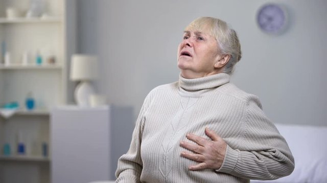Elderly woman laughing out loud suddenly feeling heart attack, health problems