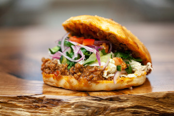 Tasty grilled prawn and beef burger with lettuce and mayonnaise served on pieces of brown paper on a rustic wooden table of counter, with copyspace