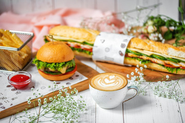 delicious lunch with cappuccino, sandwich, hamburger with french fries