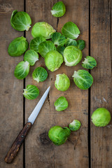 Frischer Rosenkohl zusammen mit einem Messer auf einem alten Holzuntergrund