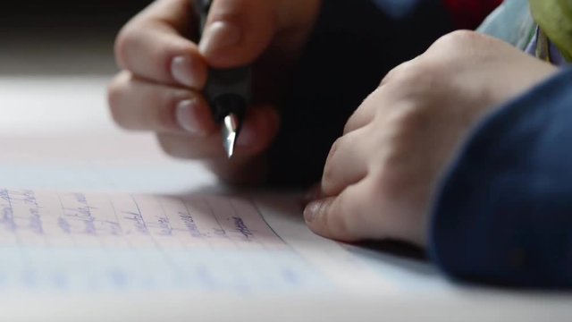 A pair of kids hands writing on paper very close up shot