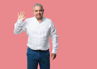 Middle aged man showing number five, symbol of counting, concept of mathematics, confident and...