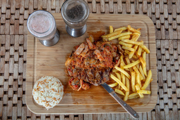Tender grilled porterhouse or t-bone steak served with crisp golden French fries and fresh green...