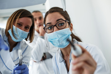 Dentist team in dental office examining patient teeth. Camera angle from patient's perspective.	