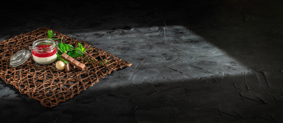 Panna cotta with strawberry jam. Sweet italian dessert from whipped cream with strawberry jam in glass jars. Dark background, copy space