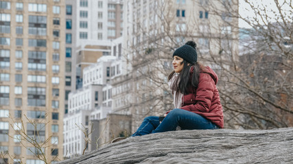 Young woman relaxes on a rock at Central Park New York