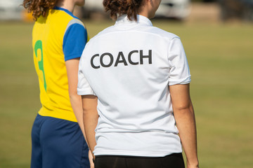 Back of sport coach wearing COACH shirt at an outdoor sport field