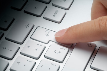 index finger pressing intro or enter key on computer keyboard