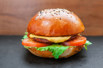 Tasty grilled prawn and beef burger with lettuce and mayonnaise served on pieces of brown paper on a rustic wooden table of counter, with copyspace