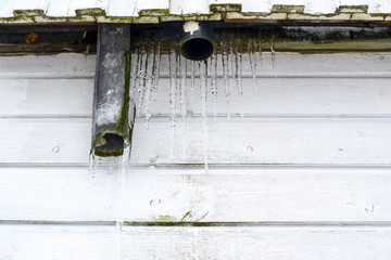 Icicles under the roof of a wooden house.