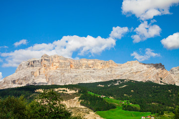 Green valley of Trentino Alto Adige, Italy, there is a village, many pine trees and the rocky mountains of the Dolomites, at high altitude from the forest