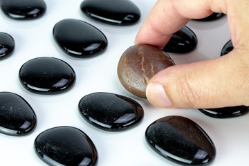 Black pebbles on white background with brown pebble.