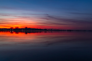 The pearly sky is beautifully reflected in the water of the Lake Zoetermeerse plas, Netherlands