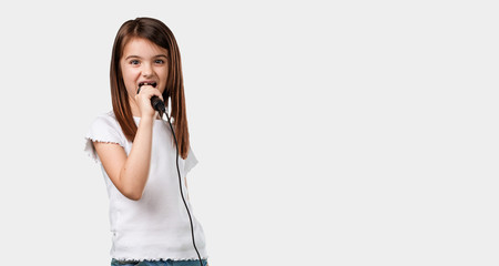 Full body little girl happy and motivated, singing a song with a microphone, presenting an event or having a party, enjoy the moment