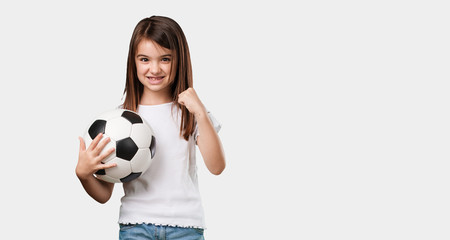 Full body little girl smiling and happy, holding a soccer ball, competitive attitude, excited to play a game