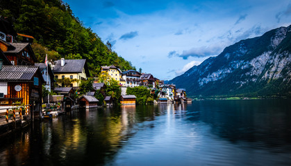 Evening scenery of lake and wooden buildings at the berth on the background of mountains in Hallstatt, Austria