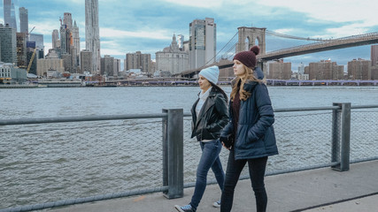 Two friends walk along the amazing skyline of Manhattan in the evening