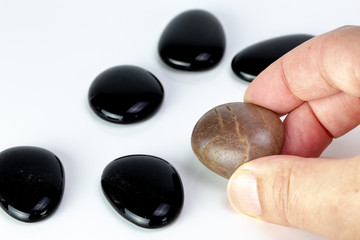 Black pebbles on white background with brown pebble.