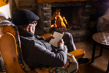 Relaxed senior man sitting in front of the fireplace - Powered by Adobe