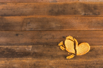 Obraz na płótnie Canvas broken biscuit heart shape on wooden table, top view