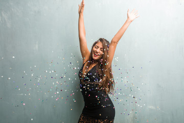 Young latin woman celebrating new year or an event. Very happy and excited, raising her arms.