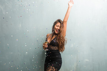 Young latin woman celebrating new year or an event. Excited and happy, holding a champagne bottle and a cup.