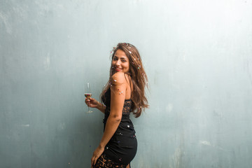 Fototapeta premium Young latin woman celebrating new year or an event. Excited and happy, holding a champagne bottle and a cup.