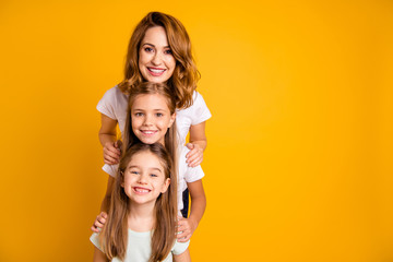 Portrait of three nice cute adorable lovely lovable attractive cheerful positive funny people standing in order of height having fun isolated over bright vivid shine yellow background