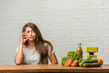 Concept of diet. Portrait of a healthy young latin woman keeping a secret or asking for silence,...