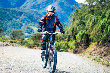 Girl in special suit and equipment riding a bike on the background of mountains