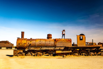 Girl on rusty steam locomotive near Uyuni in Bolivia. Cemetery trains.