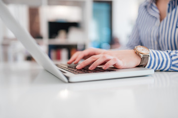 Hands of female office worker typing on laptop.