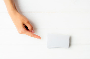 Woman showing on a white business card in hands. Tamplate for your design.