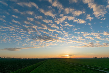 Sunset with altocumulus clouds over the dutch polder landscape near Gouda.  Scenic picture with a beautiful sky with sheep clouds over the dutch countryside. - obrazy, fototapety, plakaty