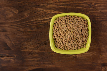 Yellow lentil in a bowl on wooden background