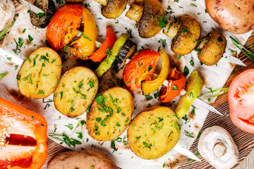 Variety of BBQ grilled vegetables lunch. skewers with  potatoes, tomatoes, mushrooms, eggplants, zucchinis  on  wood background.