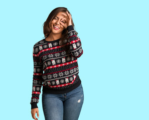 Full body young woman wearing a christmas jersey confident doing ok gesture on eye