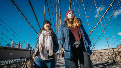 Two friends in New York walk over the famous Brooklyn Bridge