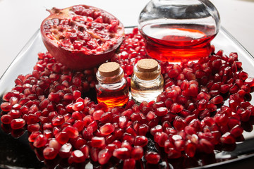 Pomegranate oil in a bottle and pomegranate seeds on a dark background