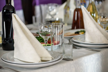 Beautiful table setting with crockery and flowers for a party, wedding reception or other festive event. Glassware and cutlery for catered event dinner