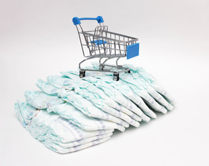 Baby diapers on a white background and a shopping trolley, the concept of buying hygiene products...