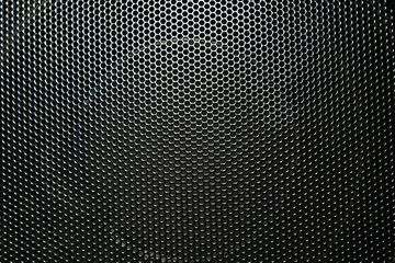 The speaker of a musical column hidden behind a grid with a pattern of rhythmically arranged holes