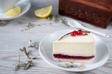 Cheesecake with berries on white plate, cup of tea on white wooden table background  with copy space 