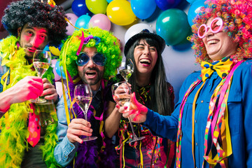 Obraz na płótnie Canvas Lachende Freunde in bunten Kostümen trinken Sekt bei einer Karneval party .