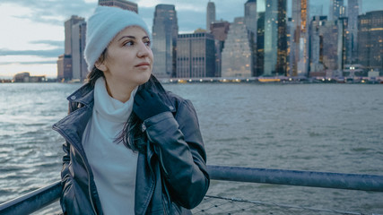 Young woman walks along the wonderful skyline of Manhattan in the evening