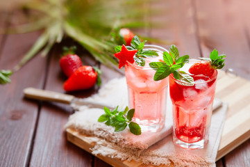 Sparkling pink strawberry lemonade on dark wooden background